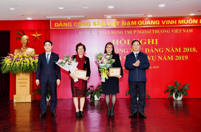 Ủy ban kiểm tra Trung ương (ngoài cùng bên phải) và Đ/c Nghiêm Xuân Thành - Ủy viên BCH Đảng bộ Khối Doanh nghiệp Trung ương, Bí thư Đảng ủy, Chủ tịch HĐQT Vietcombank (ngoài cùng bên trái) trao Kỷ niệm chương “Vì sự nghiệp kiểm tra của Đảng” năm 2018 và tặng hoa cho 02 Đảng viên thuộc Đảng bộ Vietcombank