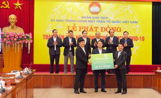 Đồng chí Nghiêm Xuân Thành - Chủ tịch HĐQT Vietcombank (đứng giữa) trao biển tượng trưng số tiền ủng hộ công tác phòng, chống dịch COVId-19 của Vietcombank tại Lễ phát động Toàn dân ủng hộ phòng, chống dịch COVId-19 do UBTƯMTTQ Việt Nam phát động với sự chứng kiến của Thủ tướng Chính phủ và lãnh đạo các bộ, ban, ngành.