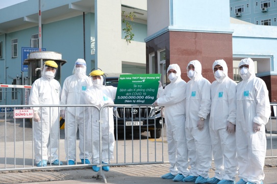 Đại diện Vietcombank, Phó Tổng Giám đốc Nguyễn Thanh Tùng (thứ tư từ phải sang) trao kinh phí hỗ trợ phòng chống COVID-19 cho TS.BS Nguyễn Tiến Quang - Bí thư Đảng ủy, Chủ tịch Hội đồng Quản lý Bệnh Viện (thứ 3 từ trái sang), đảm bảo giãn cách và an toàn phòng chống dịch theo quy định.