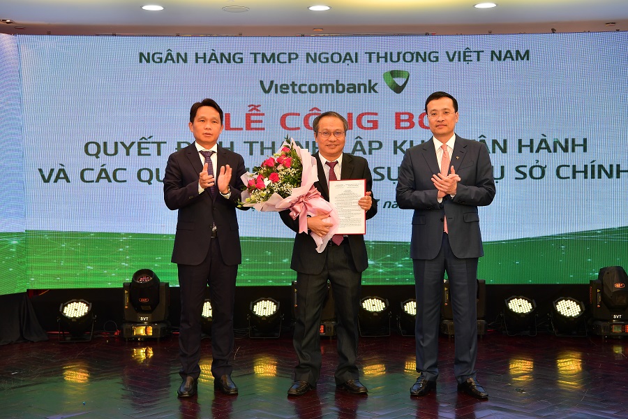 Phạm Quang Dũng - Chủ tịch HĐQT (bên phải) trao quyết định và ông Nguyễn Mạnh Hùng – Thành viên HĐQT tặng hoa chúc mừng tân Trưởng Nhóm Nghiên cứu Vietcombank - Tiến sỹ Nguyễn Thắng.